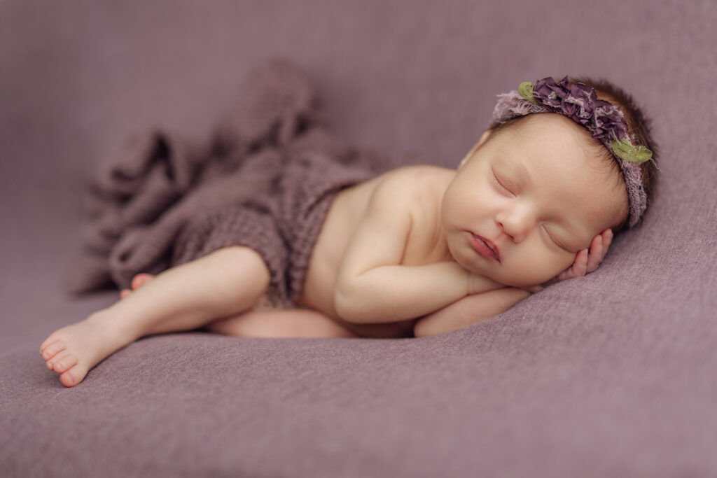 newborn girl on purple fabric at Kelly Adrienne Photography