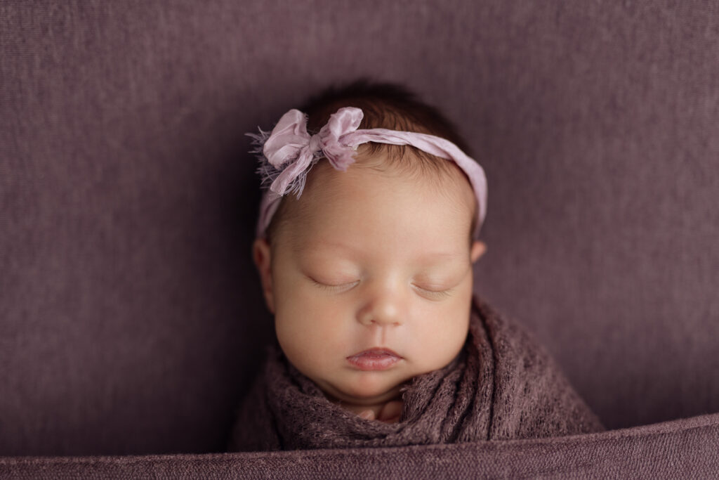 newborn girl on purple fabric at Kelly Adrienne Photography