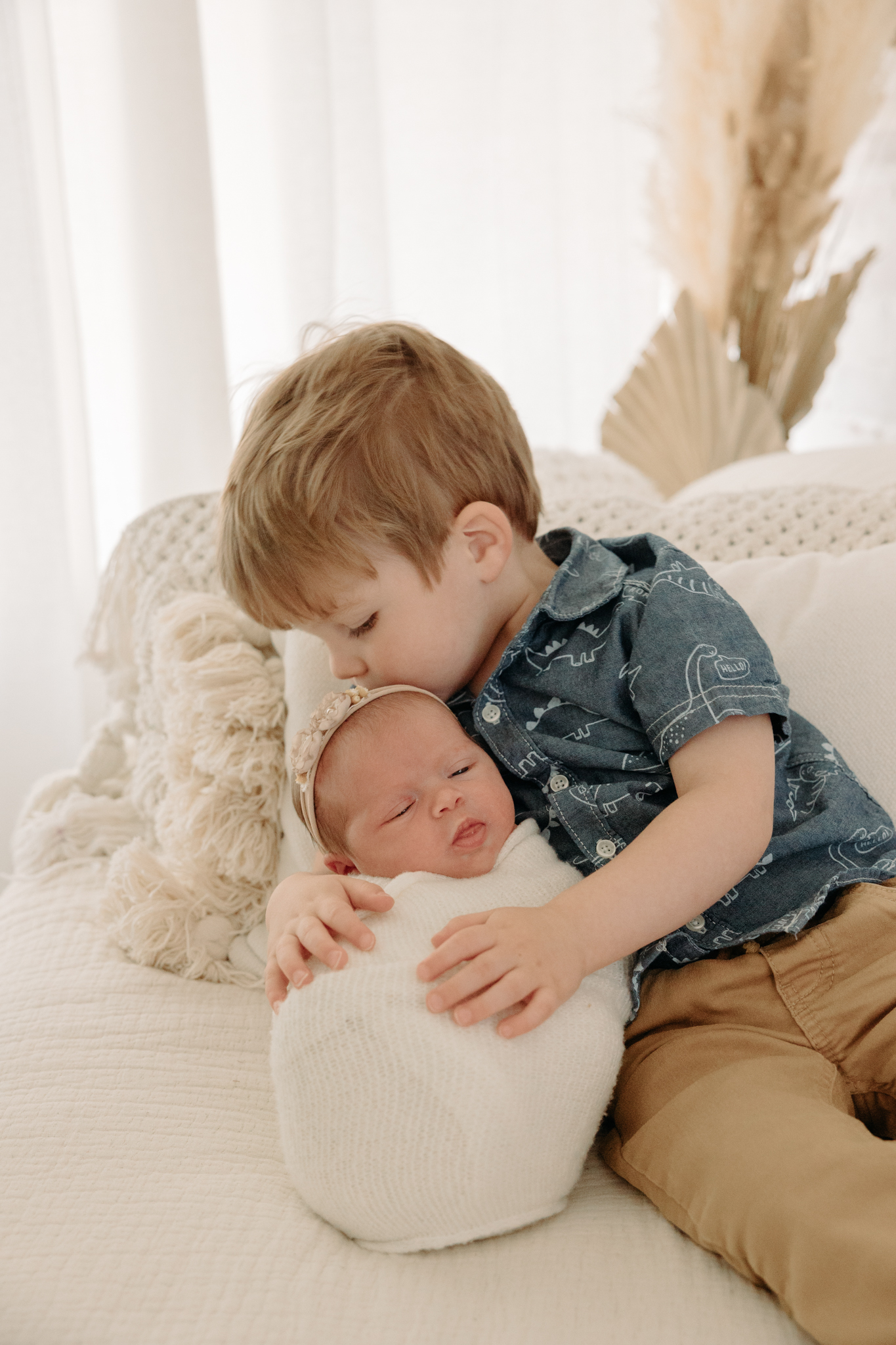 big brother kissing baby sister's head at newborn photo shoot in Pittsburgh