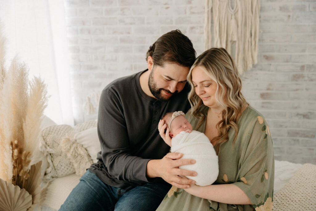 a family at their newborn session, sitting on bed