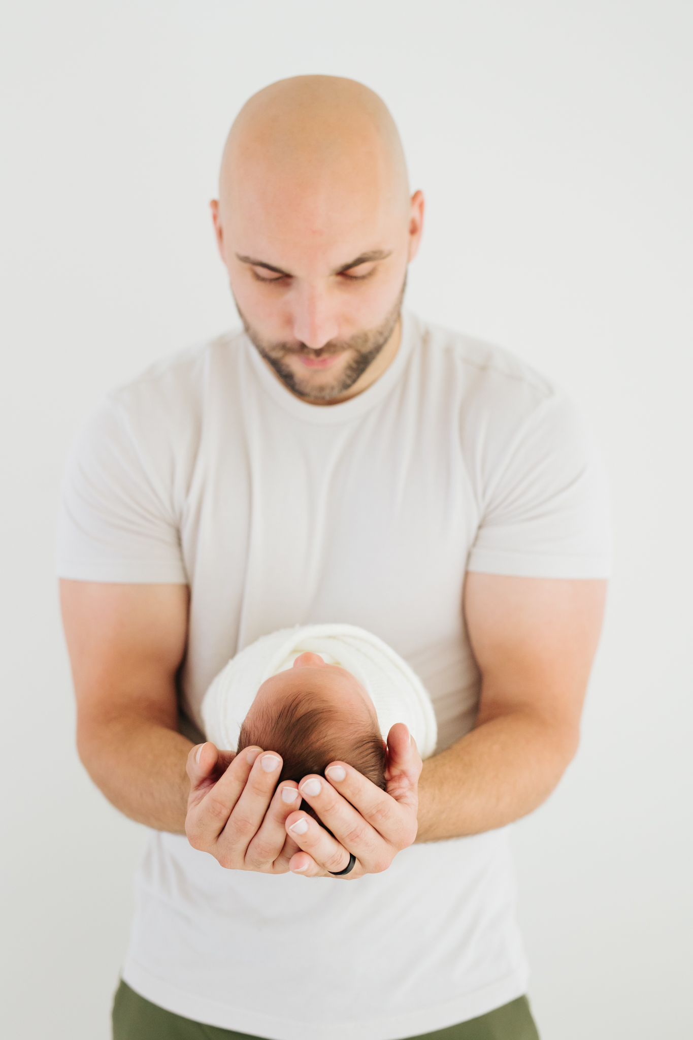 father in a white t-shirt holding his newborn baby | how to feel comfortable in front of the camera