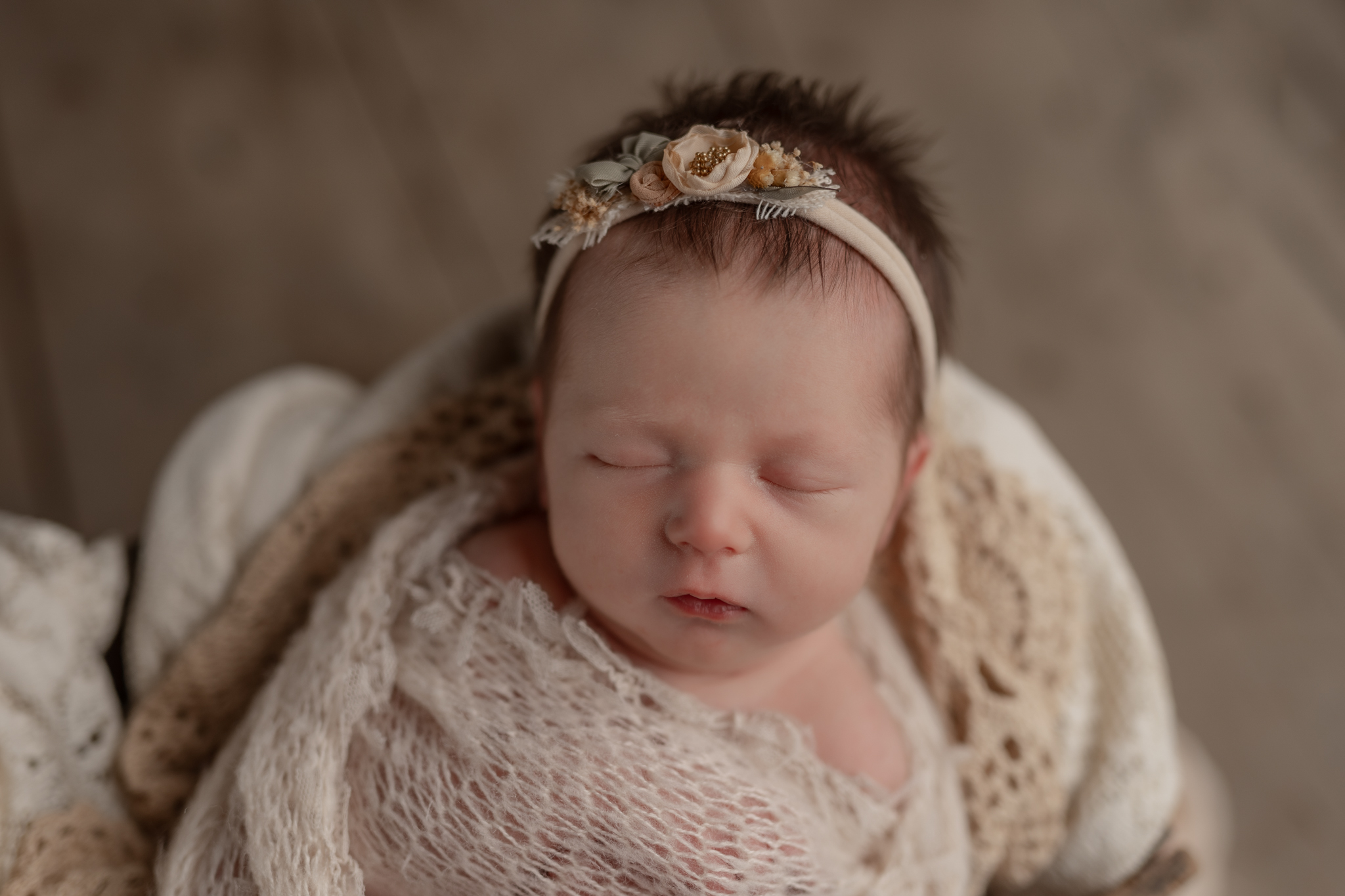 portrait of a sleeping baby girl wrapped in a neutral blanket with a matching headband. Questions to ask  your newborn photographer