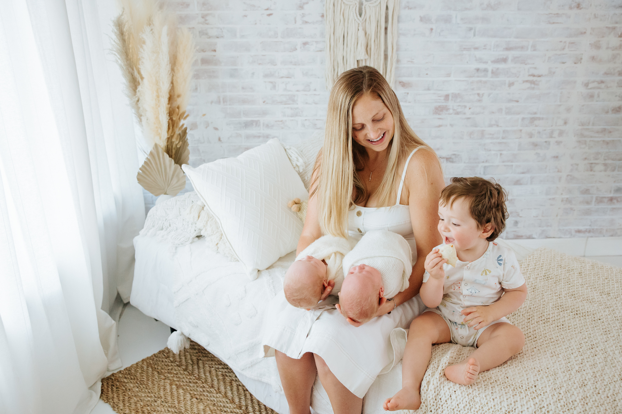 mom smiling at her son and twin baby boys at newborn photo shoot