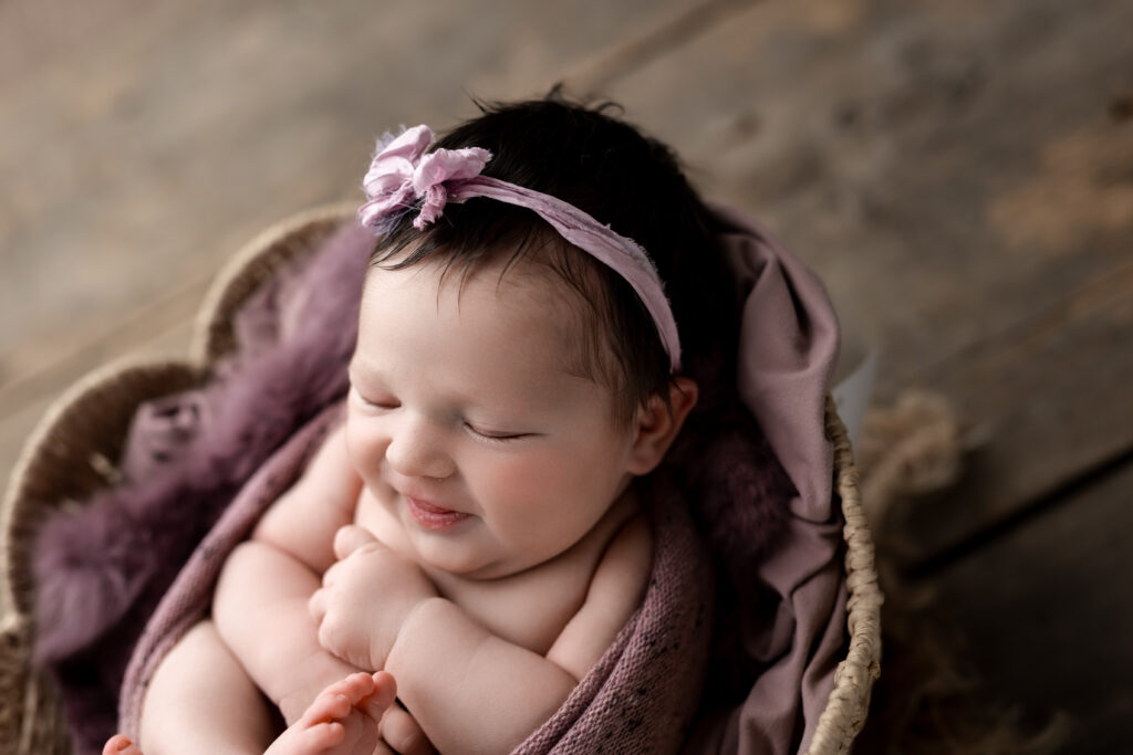 smiling baby girl in purple at newborn photos